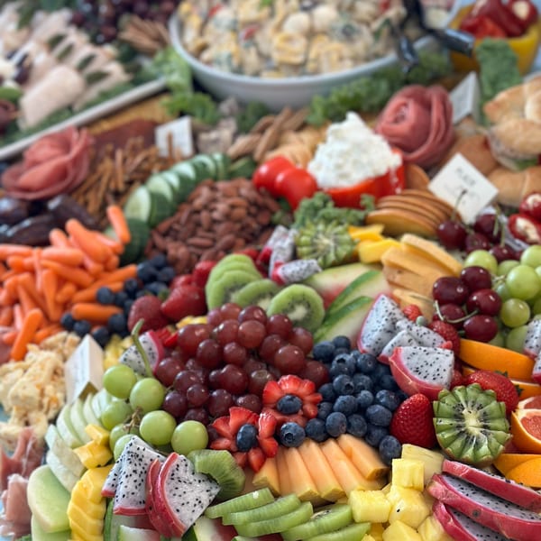 A large Harvest deli platter overflowing with meats, cheeses, fruits, and vegetables.