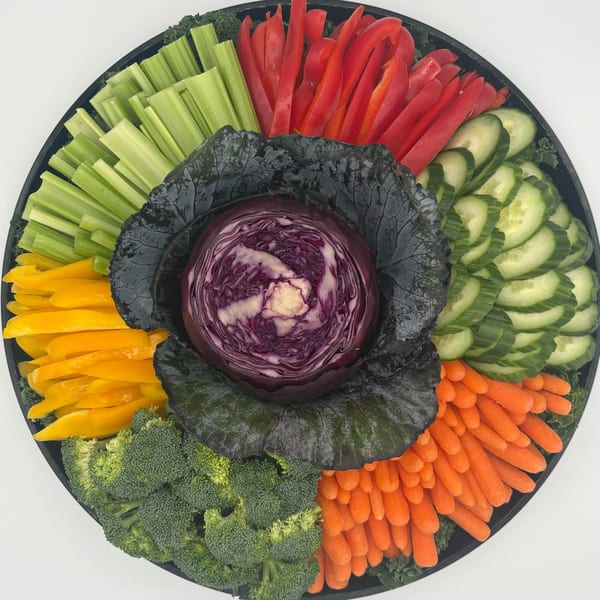 A Harvest deli vegetable platter with red cabbage, celery, bell peppers, cucumbers, broccoli, and carrots.