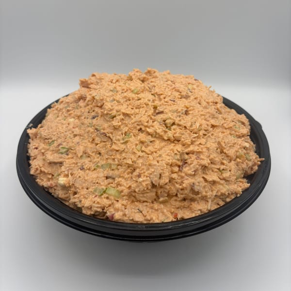 A large black bowl filled with Harvest deli's creamy orange chicken salad with visible celery pieces.