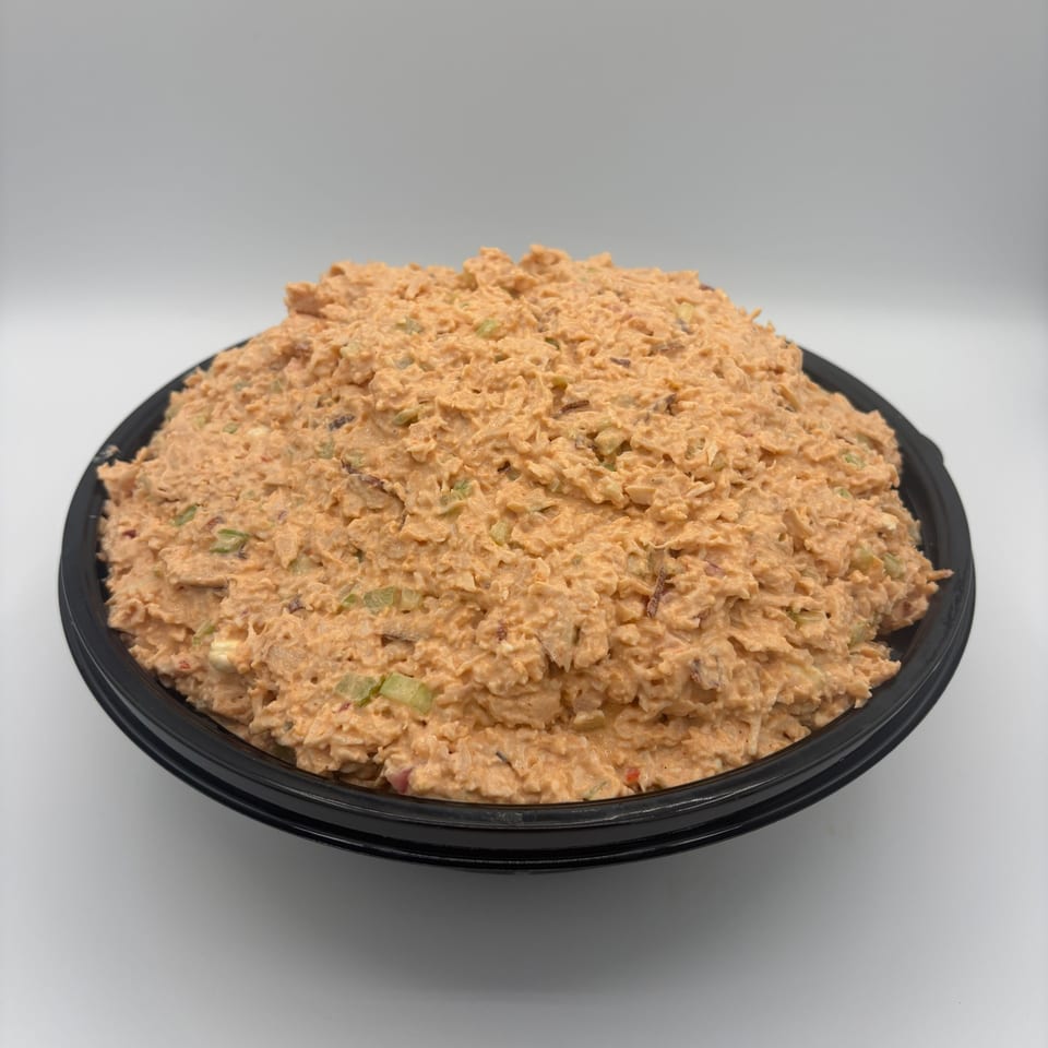 A large black bowl filled with Harvest deli's creamy orange chicken salad with visible celery pieces.