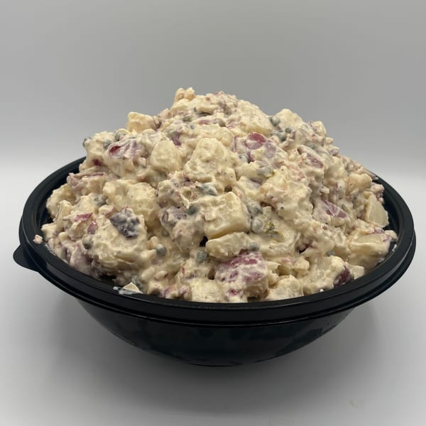 Harvest deli's potato salad in a black bowl, featuring red-skinned potatoes and creamy dressing.