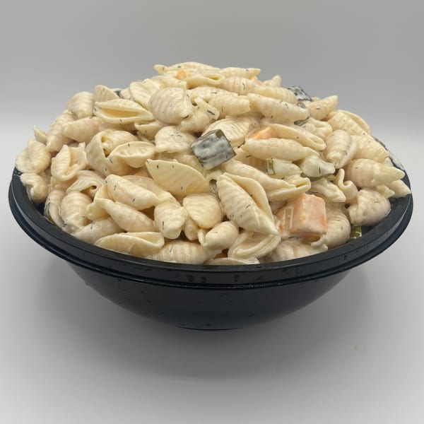 Harvest deli's pasta salad with shell noodles, creamy dressing, dill, and diced pickles in a black bowl.